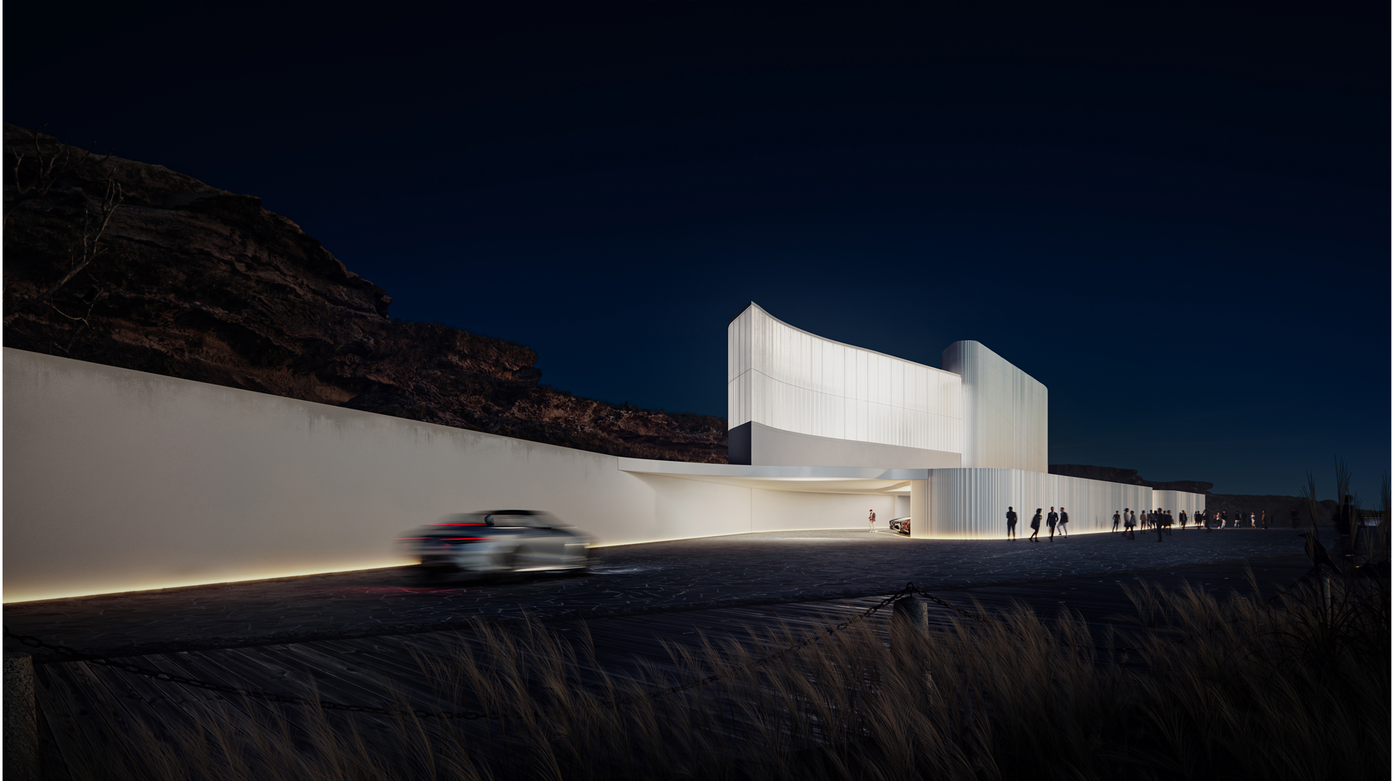 Modern white building at night with curved design and illuminated entrance, car passing by.
