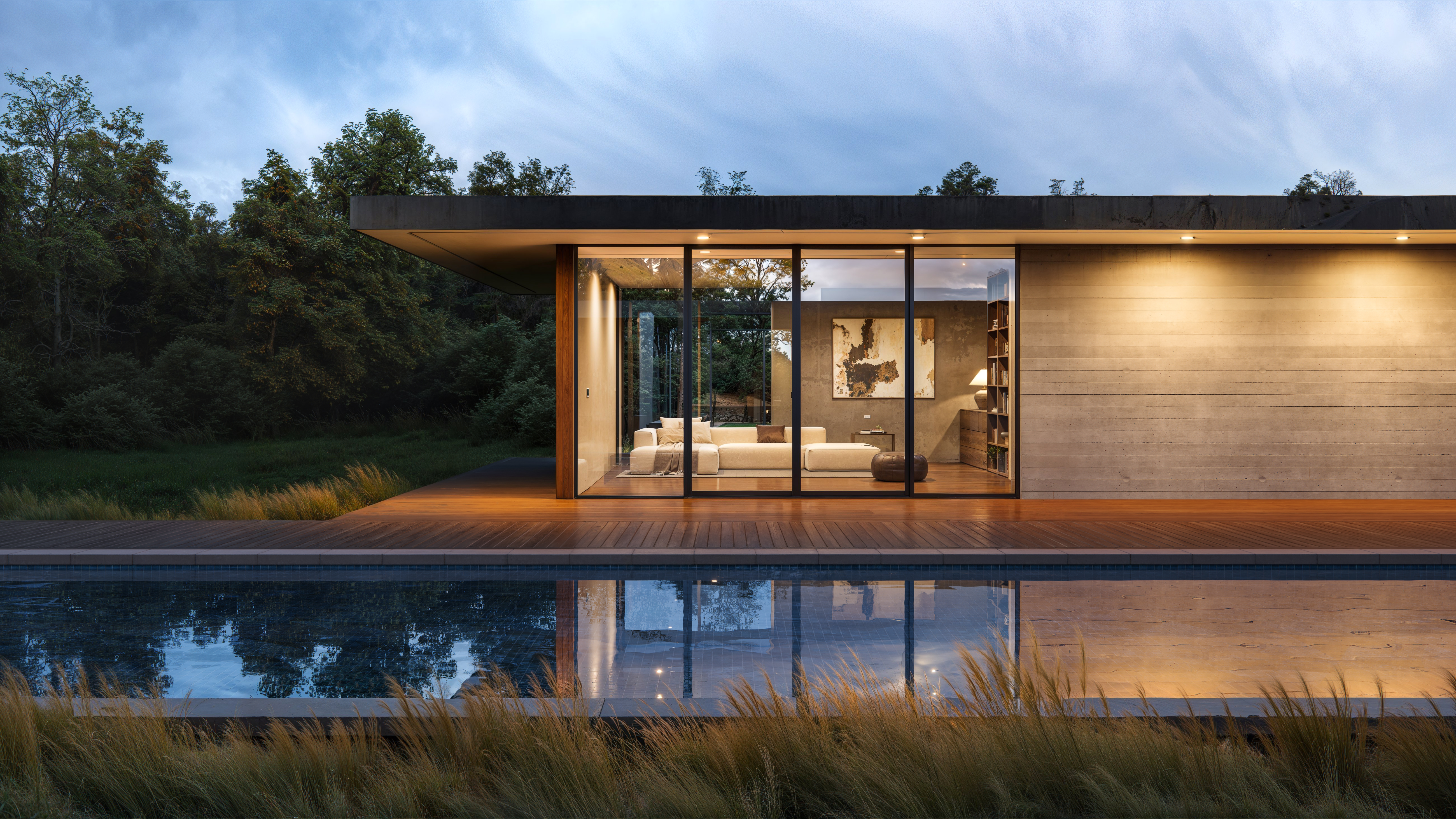 Modern house with floor-to-ceiling windows, reflecting on a pool at dusk.